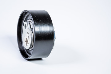 Tension roller of a timing belt of an internal combustion engine on a gray background. The concept of new spare parts and maintenance of vehicles