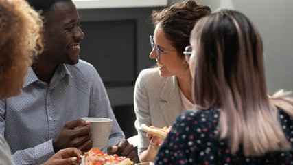 Happy diverse coworkers have fun spending lunch break together