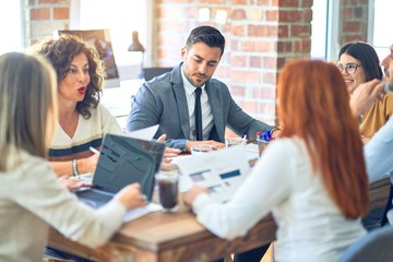Group of business workers working together. Sitting on desk using laptop reading documents at the office