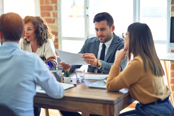 Fototapeta premium Group of business workers working together. Sitting on desk reading documents at the office