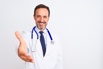 Fototapeta premium Middle age doctor man wearing coat and stethoscope standing over isolated white background smiling friendly offering handshake as greeting and welcoming. Successful business.