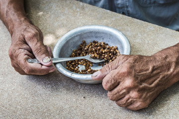 Hungry. Poor old man's hands an bowl of porridge . Selective focus. Poverty in retirement.