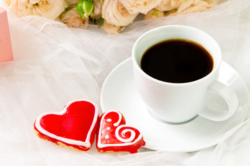 Valentine's day. Wedding . A Cup of coffee and two gingerbread heart on a background of roses.