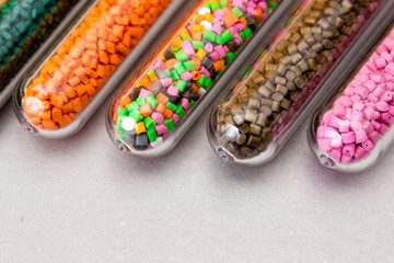 Plastic pellets .Polymeric dye in test tubes on gray background