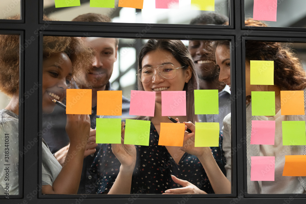 Wall mural smiling multiethnic colleagues brainstorm using post it stickers