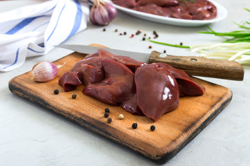 Raw chicken liver on a cutting board, knife on the table. Offal. Ready to cook. Dishes from the liver.