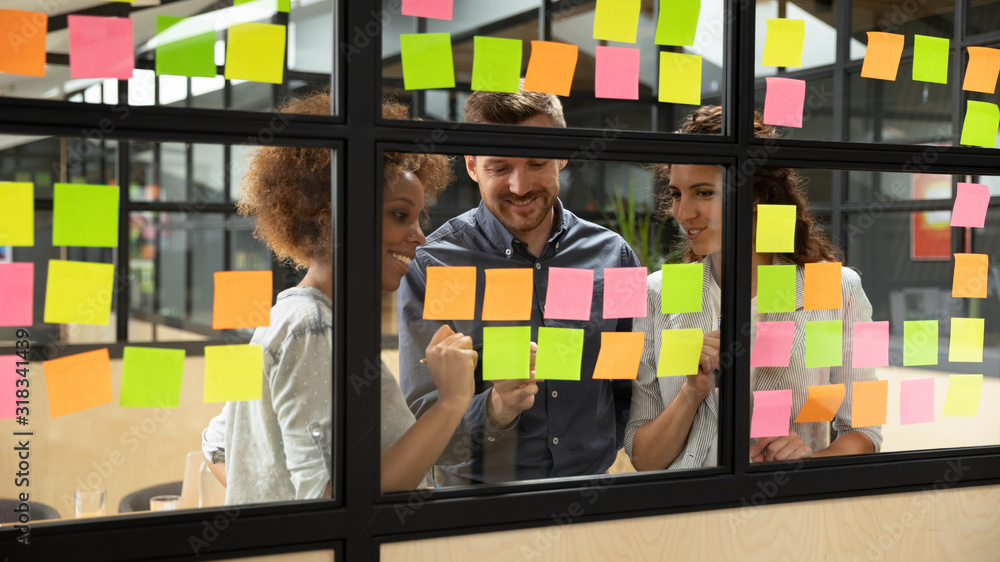 Wall mural smiling multiethnic colleagues brainstorm working with sticky notes