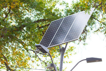 Solar device with street lamp on background of blue sky. Street light powered by solar panel with...
