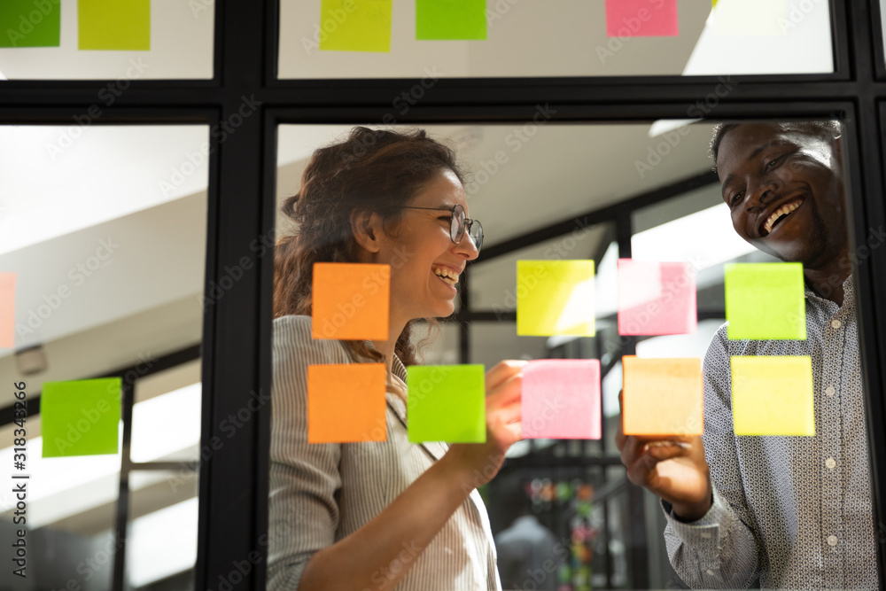 Wall mural smiling multiethnic colleagues collaborate project on sticky notes
