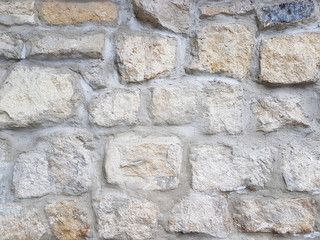 Ancient medieval stone masonry. Texture of a fragment of a wall of an old structure. A background for design and creative work. Decoration and exterior decoration of the building. Construction works