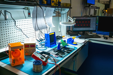 Table in the engineering lab. Radionics. Testing of printed circuit boards. The soldering of the...