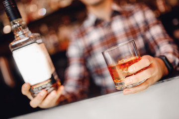 Barman holds out glass of whiskey with ice to male visitor. Concept rest in bar