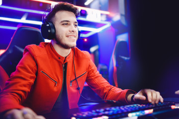 Streamer young man rejoices in victory professional gamer playing online games computer with headphones, neon color © Parilov