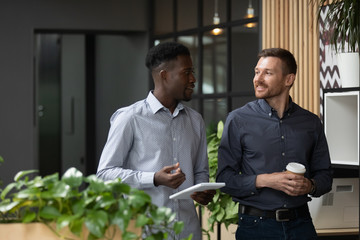 Multiethnic male colleagues stand talking discussing ideas