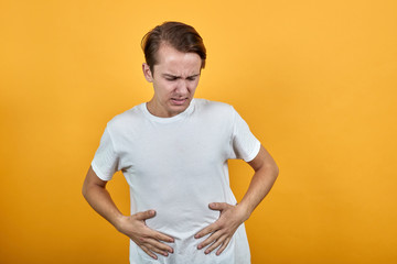 Man in white t-shirt diarrhea health problems on yellow background