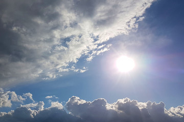 The sun shines through the cumulus clouds in the blue sky. Background and texture for artists and...