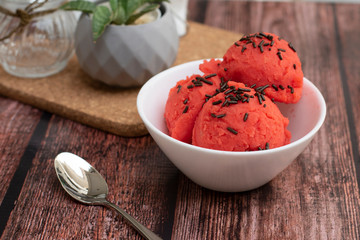 BERRIES ICE CREAM IN WHITE BOWL ON WOODEN TABLE