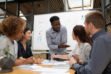 Diverse colleagues busy brainstorming discussing paperwork at briefing