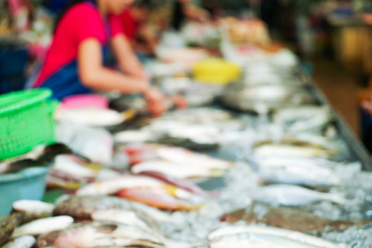 Blurred picture of raw fresh fish on the tray for selling in the market with blurred seller in background