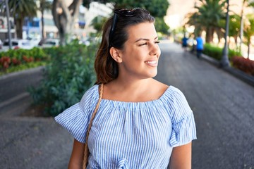 Fototapeta premium Young beautiful woman smiling happy walking on city streets on a sunny day of summer
