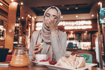 modest muslim woman having lunch at a table in a cafe