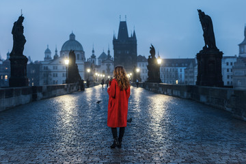 Female tourist walking alone on the Charles Bridge during the early morning in Prague, capital of...