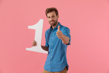happy guy holding number one sign and making thumbs up sign