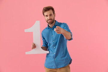 happy casual guy holding number one sign and pointing finger