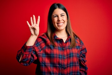Young beautiful woman wearing casual shirt over red background showing and pointing up with fingers number four while smiling confident and happy.