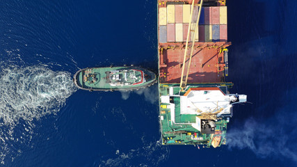 Aerial drone photo of cargo container ship guided by tug assistive boat to Mediterranean logistics...