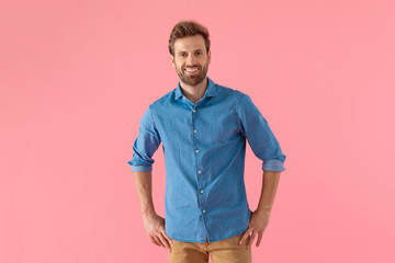 happy casual man in denim shirt smiling and holding hands on hips