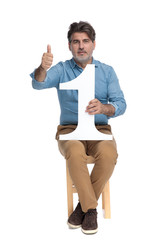 Positive casual man giving a thumbs up, holding number one
