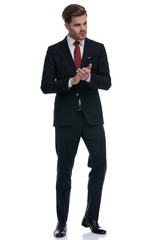 elegant businessman in suit rubbing palms and looking to side