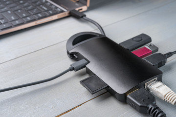 USB Type C adapter or hub connected to the laptop with various accessories - pendrives, hdmi, ethernet, memory card, cables.