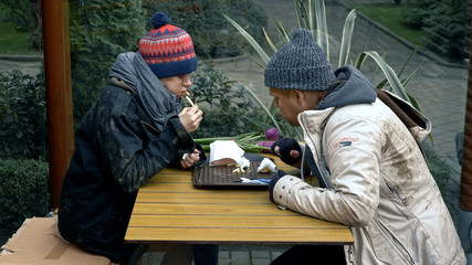 homeless couple, man and woman eating leftovers from a table in a street cafe
