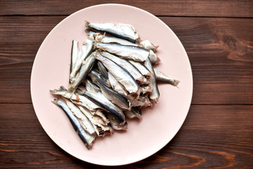 Raw gutted fish sprats, herring on a plate on a wooden background.