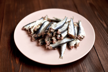 Raw gutted fish sprats, herring on a plate on a wooden background.