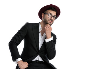 formal business man sitting and touching chin while looking away