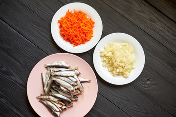 Raw herring fish, sprats and chopped onions and carrots. Preparation for cooking fish with...