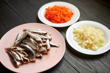 Raw herring fish, sprats and chopped onions and carrots. Preparation for cooking fish with...
