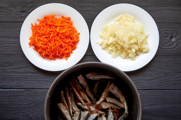 Raw herring fish, sprats and chopped onions and carrots. Preparation for cooking fish with vegetables.