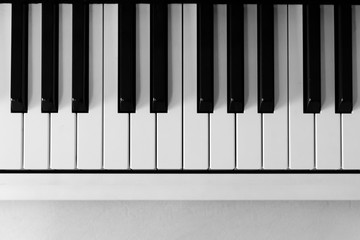 View from above of a piano keyboard on the upper half of frame. Copy space