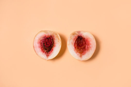 The two halves of the peach on a pastel background. Flat lay, top view.