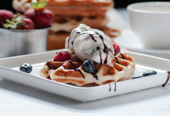 waffle and berry ice cream, strawberries, blueberries. served on a white plate and on a white table