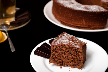 Fototapeta na wymiar A piece of chocolate cake on a white plate on a black table