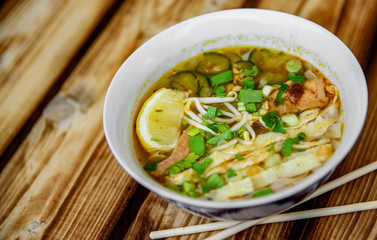 Spicy asian soup in bowl on wooden table background