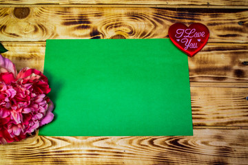 peony flower and two red hearts near paper on a wooden background, valentines day, the day of all lovers