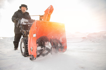 Man cleaning snow from sidewalks with snowblower machine winter