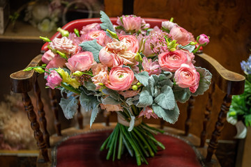 Beautiful multi-colored bouquet of mixed roses and other greens in a flower shop on vintage chair. Fresh cut flowers.