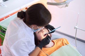 Female dentist treating teeth to patient, young man in chair at dental clinic. Dentistry, healthy teeth, medicine and healthcare concept